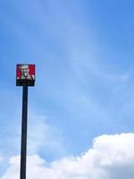 Bangkok, Tailandia. 23 de junio de 2021. logotipo de kfc en el cartel del poste en el fondo del cielo azul. Kentucky Fried Chicken es una cadena mundial de restaurantes de comida rápida que vende pollo frito. foto