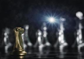piezas de ajedrez de caballero dorado frente al ajedrez de plata frontal a bordo con luz de bengala para triunfar en la competencia. estrategia de gestión o liderazgo y concepto de trabajo en equipo. foto