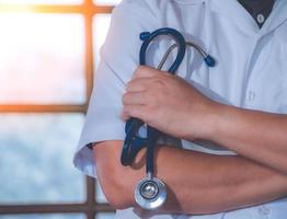 Male Doctor With Arms Crossed Holding Stethoscope in hospital. Healthcare and medicine concept. photo