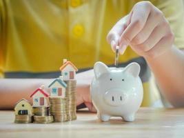 Asian boy holding coins drop a container saving money to save money invest for future and buy home.Concept loan, property ladder, financial, real estate investment and bonus. photo