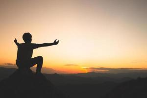 silueta con brazos extendidos en concepto de puesta de sol para religión, adoración, oración y alabanza, el poder de la esperanza o el amor y la lealtad. fe en la bondad. poder del éxito. foto