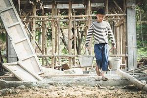 los niños que trabajan en las obras de construcción se ven obligados a trabajar. el concepto de lucha contra el trabajo infantil. el abuso del trabajo. la opresión o intimidación del trabajo forzoso entre los niños. foto