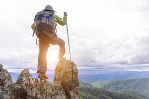 Active climbers enjoy the view.female backpacker with backpack and crutches enjoy the sunshine on the mountain, copy space. photo