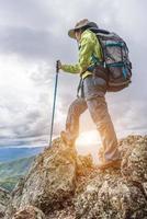 mujer joven viajera con mochila elegante mirando hacia adelante a la increíble vista de las montañas. disfrutar de la naturaleza, relax, placer. foto