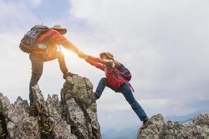 pareja joven viajando, ayudando, mujer excursionista recibiendo ayuda en la caminata sonriendo feliz superando obstáculos, mochileros turísticos caminando en el bosque. foto