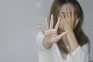 El primer plano de una joven muestra un gesto de parada con la mano diciendo no a la violencia doméstica o al abuso foto
