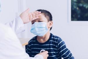 el médico se sienta en el trabajo, examinando a un niño paciente. foto