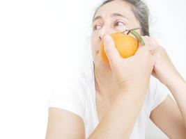 mujer de cuarenta y nueve años con una camiseta blanca sobre un fondo blanco con una naranja foto