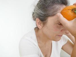 Forty nine year old woman in a white T-Shirt against a white background with an orange photo