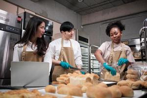 Three young friends and startup partners of bread dough and pastry foods busy with homemade baking jobs while cooking orders online, packing, and delivering on bakery shop, small business entrepreneur photo