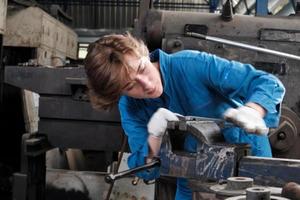 One professional young female industry engineer worker works in a safety uniform with metalwork precision tools, mechanical lathe machines, and spare parts workshop in the steel manufacturing factory. photo