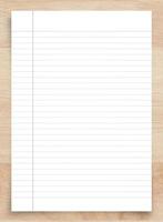 White paper sheet on wood with clipping path. White notebook paper with line pattern background. photo