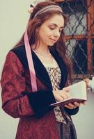 Portrait of brunette woman dressed in historical Baroque clothes  reading book, outdoors photo