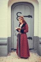 Portrait of brunette woman dressed in historical Baroque clothes  reading book, outdoors photo