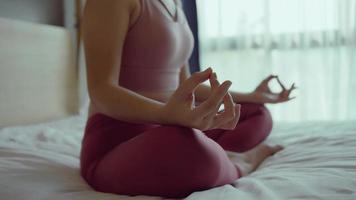 primer plano mano de mujer en ropa deportiva práctica yoga loto posar para meditar en casa, mujer de bienestar haciendo yoga para respirar y meditar cómoda y relajada. video