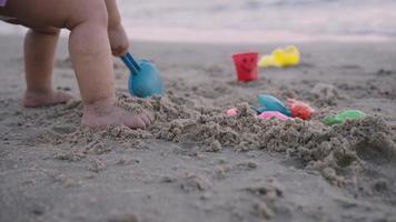 Baby girl is playing sand on beach. video