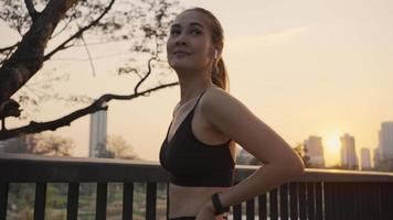 portret van mooie vrouw in sportkleding glimlach, en kijk rond na een training voor de gezondheid in de avond in het openbare park. video