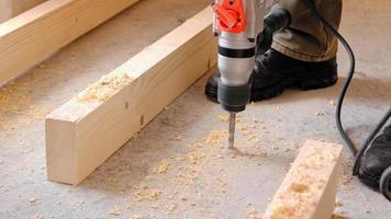 percer des trous dans le sol en béton de la maison avec une perceuse pour l'installation de rondins de plancher en bois. construction et réparation de vos propres mains video