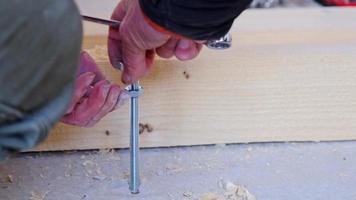 Hands of master twist washer with nut onto a threaded steel stud into concrete floor of rough floor for installation of wooden floor log. Repair and construction with your own hands - DIY. Slow motion video