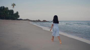 vista traseira crianças felizes está correndo na praia. video