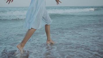 criança feliz garota pernas e pés correndo ao longo das ondas de água do mar na praia. video