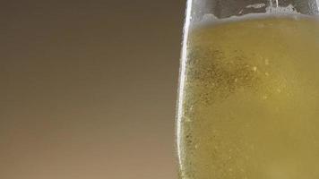 Pouring cold golden light beer into a glass. Craft beer making bubbles and foam. video