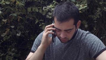 jeune homme parlant avec un téléphone portable dans le concept extérieur de la nature video