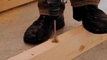 percer des trous dans les rondins de plancher en bois de la maison avec une perceuse pour les supports de plancher d'installation, la sciure de bois vole. perceuse à bois forstner, plume. construction et réparation de vos propres mains video