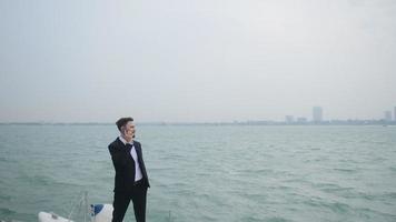 slow-motion of A young businessman in a suit is calling to contact a business on a sailboat