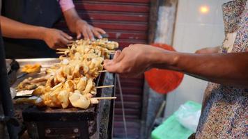Der Koch grillt den Tintenfisch auf dem Holzkohlegrill. lokale straßenmeeresfrüchte von thailand video