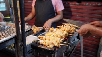 el chef está asando los calamares en la parrilla de carbón. mariscos callejeros locales de tailandia video
