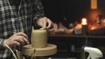 A potter makes a clay teapot with his own hands