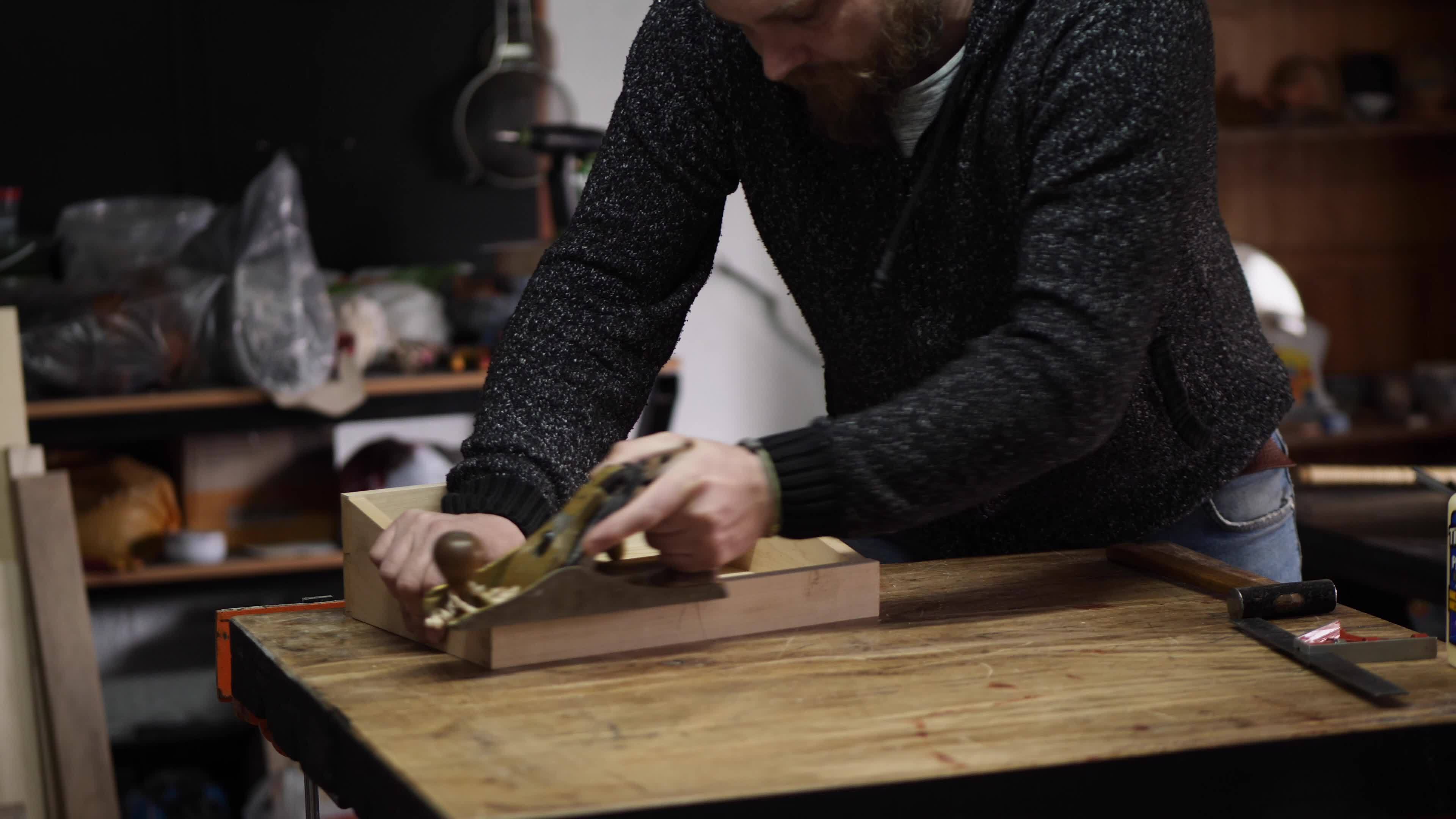 a carpenter using a hand planer levels the surface of a walnut wood ...