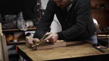 un falegname usando una pialla a mano livella la superficie di un grezzo di legno di noce video