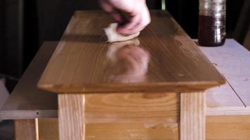A carpenter applies oil to an ash table top video