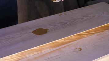 um carpinteiro aplica óleo em uma mesa de cinzas video