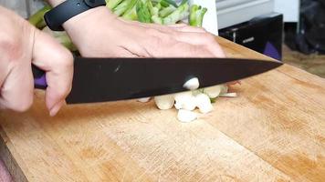 una donna taglia le cipolle verdi per ulteriore essiccazione in un braciere video