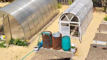 växthus och tunnor med vatten för att vattna i trädgården video
