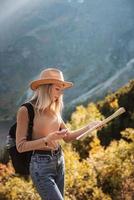 pasión por los viajes y concepto de viaje. chica viajera elegante con sombrero mirando el mapa, explorando bosques.