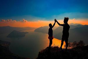 un par se da la mano en señal de victoria en la cima de una montaña foto