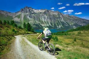 motociclista en camino de tierra de montaña en un hermoso paisaje en los alpes foto