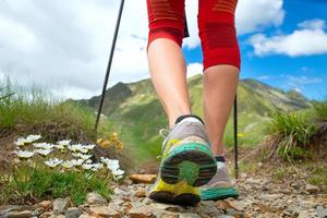 Feet of a woman who hikes in the mountains with nordic walking sticks photo