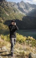 joven fotógrafo tomando fotografías con cámara digital en una montaña. foto