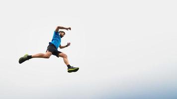 Athlete man running in the mountains during a jump in the sky photo