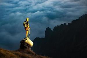 Fantastic sunset in mountains with hiker on a stone where he arr photo