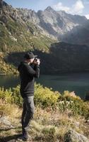 Young  man photographer taking photographs with digital camera in a mountains. photo