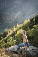 mujer joven en un viaje de senderismo sentado en una roca foto