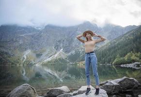 Young tourist woman in a hat with hands up on the top of the mountains photo