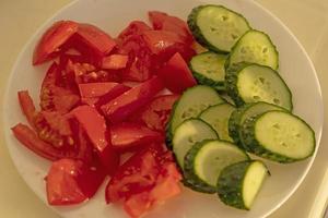 Vegetables cucumbers and tomatoes close-up on a plate photo