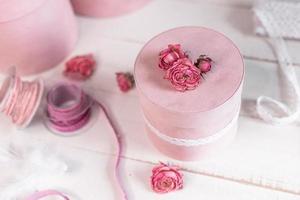 Beautiful pink round gift wrapping is decorated with narrowed roses. Romantic packaging concept photo